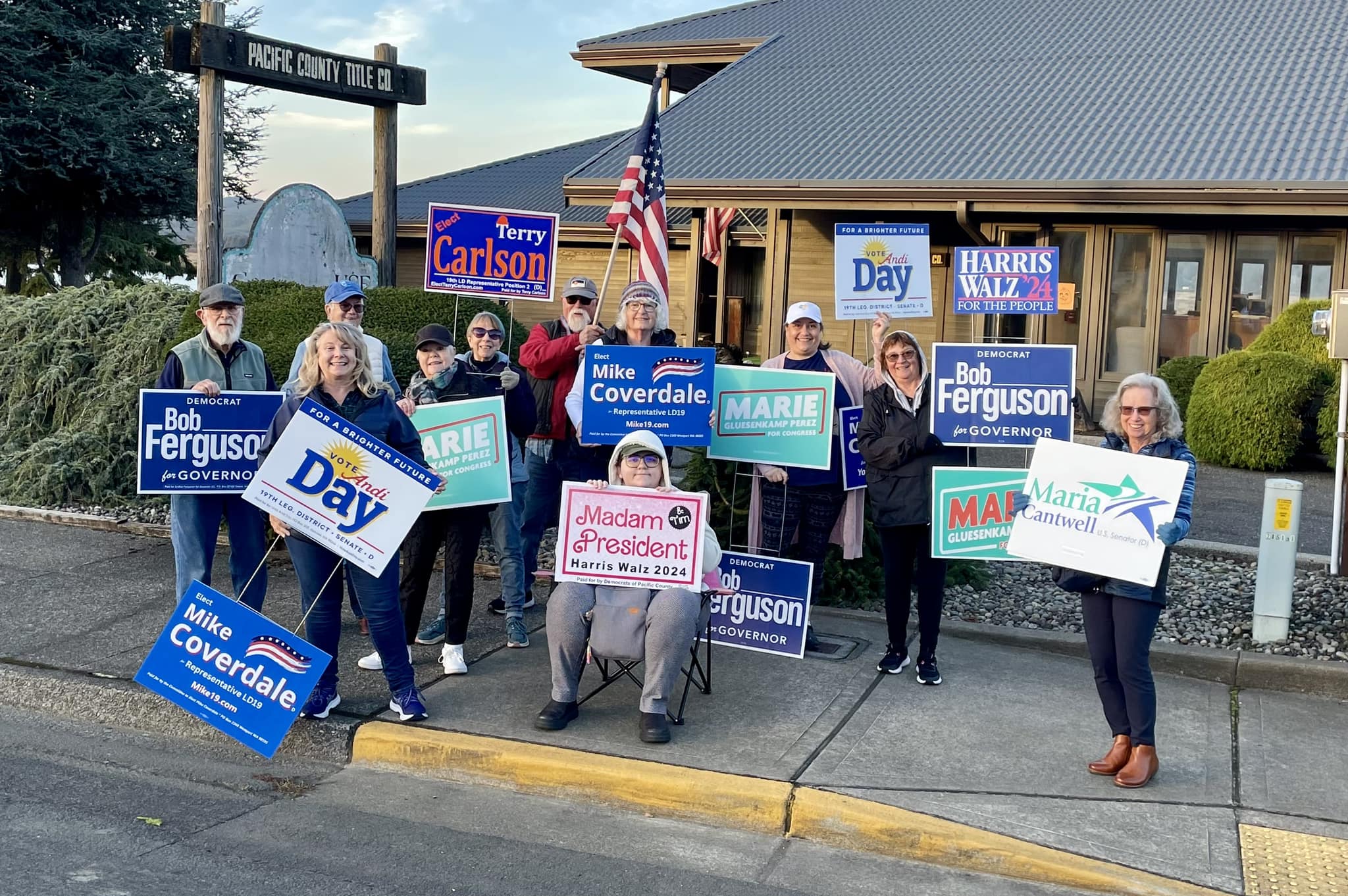 Group of people standing outside holding signs in their hands for election candidates.